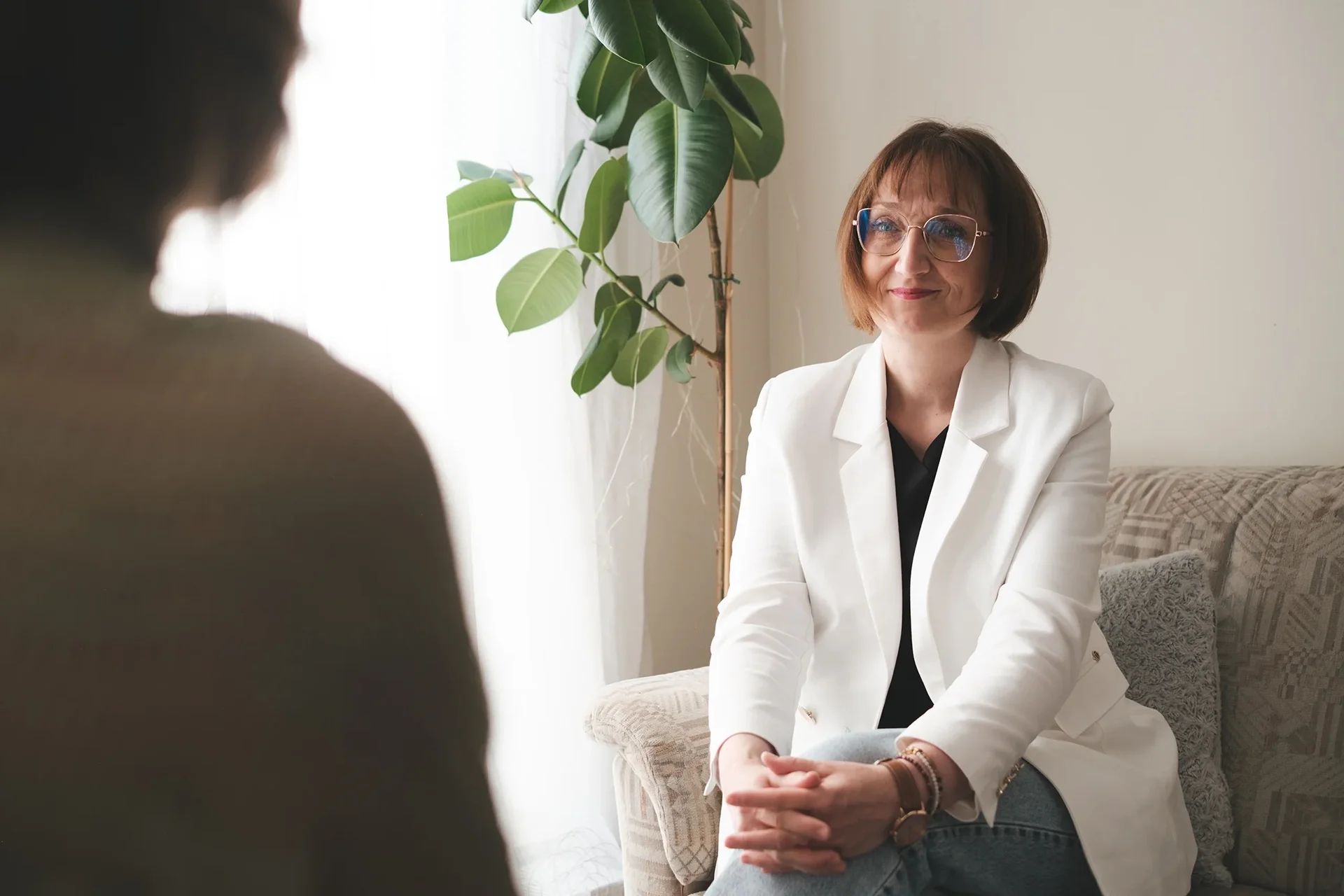 Uśmiechnięta psychoterapeutka w białej marynarce podczas indywidualnej konsultacji psychologicznej w gabinecie Liberosis.